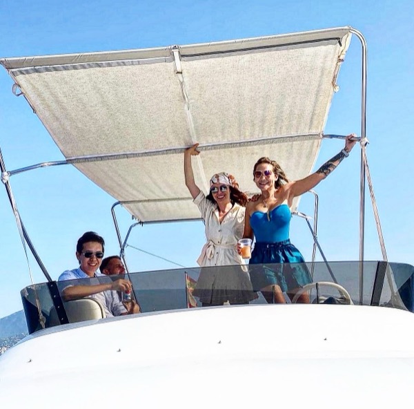 Guests under the bimini shade with drinks on a Marbella motor yacht charter